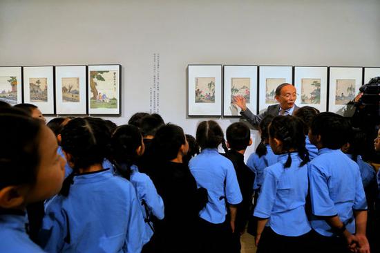 Song Feijun (facing front), a grandson of late Chinese painter Feng Zikai, gives a guided tour to children visiting the ongoing exhibition of Feng's works at the National Art Museum of China through Nov 4. (Photo provided to China Daily)