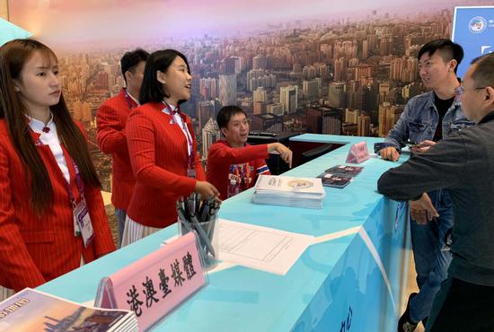 Journalists get information at the China International Import Expo media center on Friday in Shanghai. The media center officially opens on Saturday. （WANG ZHENGHUA/CHINA DAILY）