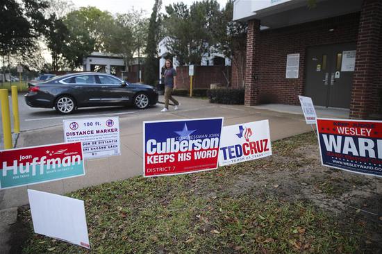 A voter walks past campaign advertisement outside a polling station in Houston, Texas, the United States, Nov. 6, 2018. U.S. voters began to cast their ballot in the midterm elections as the first polling stations opened Tuesday morning. (Xinhua/Wang Ying)