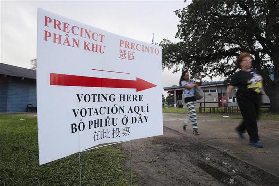Voters walk past a voting direction board outside a polling station in Houston, Texas, the United States, Nov. 6, 2018. U.S. voters began to cast their ballot in the midterm elections as the first polling stations opened Tuesday morning. (Xinhua/Wang Ying)