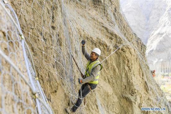 Men work on the cliff in China's Xinjiang