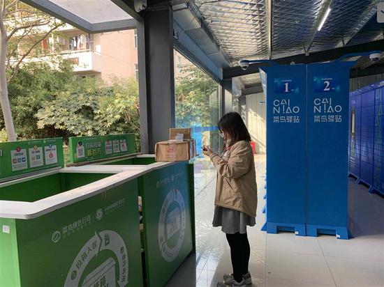 A Donghua University student puts packaging materials from her delivery back into a collection box inside a Cainiao courier service point.  (Photo/Shine.cn)