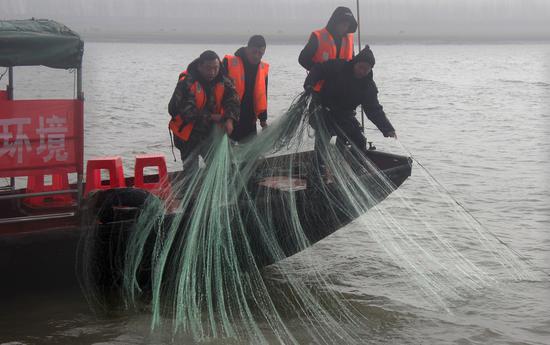 Members of a Yangtze patrol seize fishing nets placed illegally in the river in Jinzhou, Hubei.(Liu Tao/For China Daily)