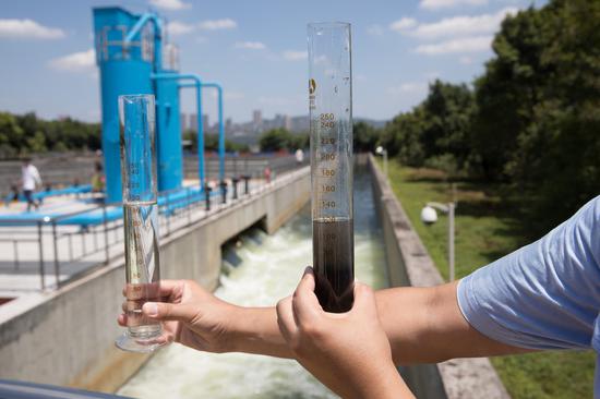 A worker compares differences in water quality at a sewage treatment plant in Chongqing.(Xinhua)