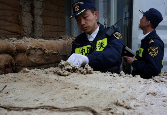 Customs officers check smuggled waste cotton in Qingdao, Shandong province, on June 11, 2018. (Photo by Zhang Jingang/For China Daily)