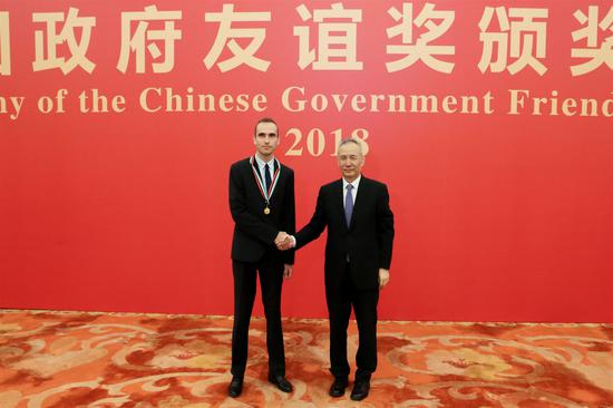 Konstantin Chingin shakes hands with Vice-Premier Liu He at the Chinese Government Friendship Award ceremony in Beijing on Sept. 29. (Photo/CHINA DAILY)