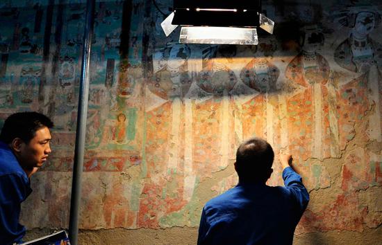 Technicians work on restoring damaged murals at the Mogao Grottoes in Dunhuang, Gansu province. (Photo/Xinhua)