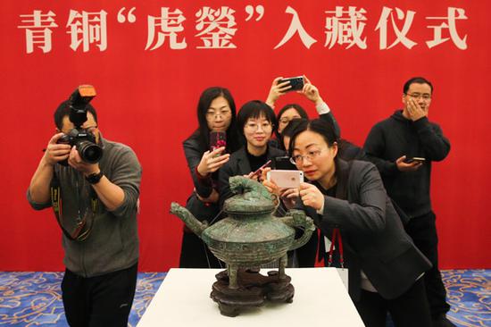 Journalists and National Museum of China employees crowd around a tiger-topped bronze relic that dates to the late Western Zhou Dynasty (c. 11th century-771 BC). The relic was returned to the museum on Tuesday after being lost abroad for more than a century. (Photo by Jiang Dong/China Daily)
