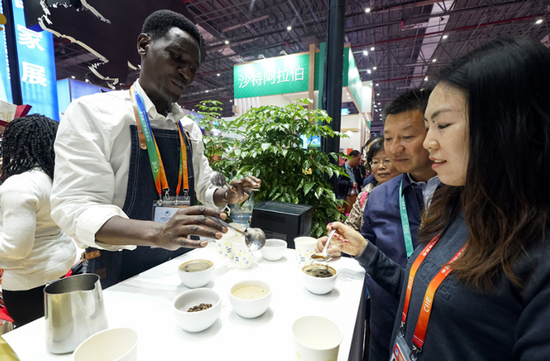 A worker from Kenya introduces his country's coffee products at the China International Import Expo. (Photo/Xinhua)