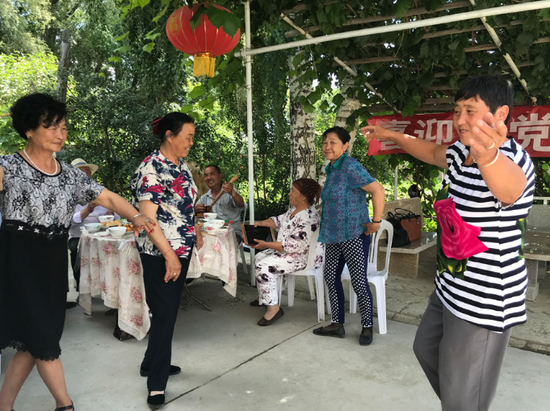 Descendants of the Huerjia, a group of Han people who arrived in Hongdun, Xinjiang Uygur autonomous region, in the 1860s, perform a folk dance with neighbors from other ethnic groups in a garden. (Photo provided to China Daily)