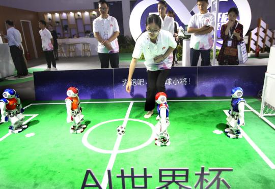 Four AI robots play football at the Huawei booth during an industry expo in Beijing. (Photo provided to China Daily)