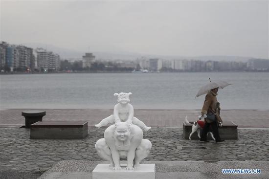 A woman walks past a sculpture by Chinese artist Xu Hongfei at the port city of Thessaloniki, Greece, on Dec 18, 2018. (Photo/Xinhua)