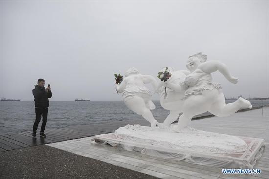 A man takes photos of a sculpture by Chinese artist Xu Hongfei at the port city of Thessaloniki, Greece, December 18, 2018. /Xinhua Photo