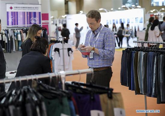 An American buyer takes notes at the booth of a Chinese clothing producer at the 2018 Chinese Textile and Apparel Trade Show in New York, the United States, July 23, 2018. (Xinhua/Wang Ying)