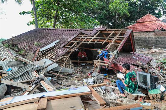 Locals have food at a damaged house in Banten Province, in Indonesia, Dec. 24, 2018. The Indonesian disaster agency on Monday put the death toll of the tsunami triggered by a volcanic eruption at 373 with 1,459 others injured, a spokesman of the agency told Xinhua on Monday. (Xinhua/Zhang Keren)