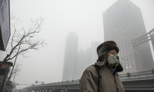 A man wearing a mask walks along a smog-shrouded street in Beijing, the capital of China, on January 29, 2013. The National Meteorological Center (NMC) issued a code-blue alert on January 27 as the smoggy weather forecast for the following two days would cut visibility and worsen air pollution in some central and eastern Chinese cities. (Photo: Li Hao/GT)