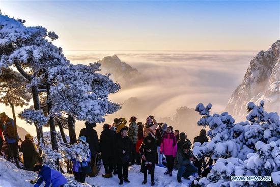 Visitors watch sunrise and clouds on Huangshan Mountain in east China