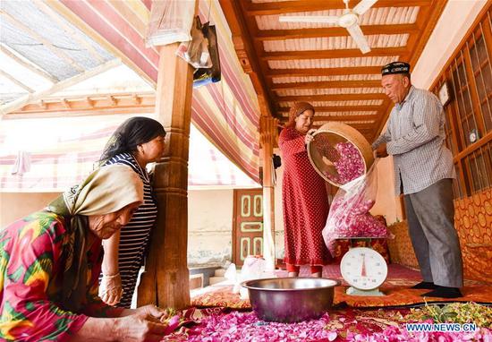 Flower grower Ruz and his wife Tajinisa weigh rose petals used for making rose sauce at a village in Hotan, northwest China's Xinjiang Uygur Autonomous Region, June 6, 2018. (Xinhua Photo)