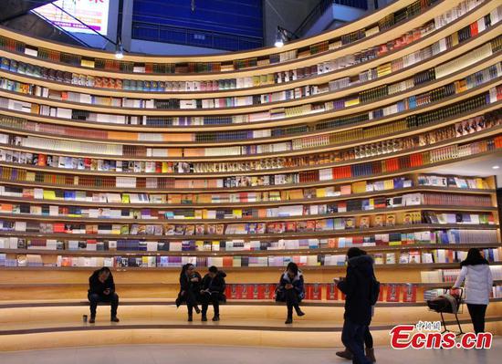 A circular wall stacked with books at a new bookstore in Hohhot, North China's Inner Mongolia Autonomous Region, Jan. 20, 2019. The innovative wraparound shelving units have attracted the interest of many visitors. (Photo: China News Service/Chen Feng)