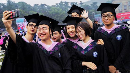 Graduates pose for photos at the 2018 commencement ceremony of Wuhan University in Wuhan, capital of Central China's Hubei province, June 22, 2018. /Xinhua Photo