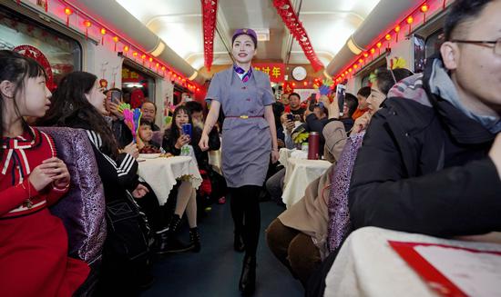 A train attendant models her clothing on a train from Qiqihar, Heilongjiang province, to Beijing on Saturday. Staff members organized a mini Spring Festival gala to entertain passengers, many of them on their way to family reunions. (Photo by Cai Yang/XINHUA)