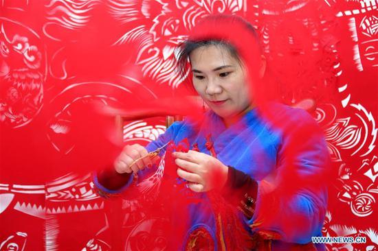 Folk artist Shi Hongxia creates a pig-themed paper cutting artwork at home in Tengzhou City, east China's Shandong Province, Jan. 31, 2019. (Xinhua/Sun Zhongzhe)