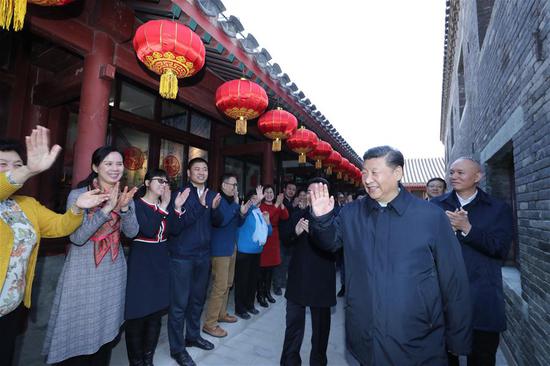 Chinese President Xi Jinping, also general secretary of the Communist Party of China Central Committee and chairman of the Central Military Commission, waves to residents as he visits a 