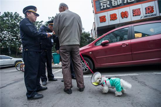 Urban management officers explain the regulations to a man walking his dog on a street in Hangzhou. (CHEN ZHONGQIU/FOR CHINA DAILY)