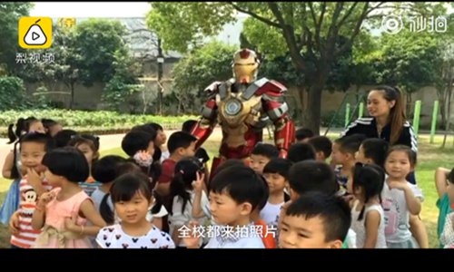 Bao Guojian wears the Iron Man outfit and takes group photo with children. (Screenshot photo/Pear Video)