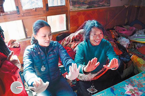 Chan shows a Tibetan woman in Qinghai province how to check her health. (Photo by CCOUC/CHINA DAILY)