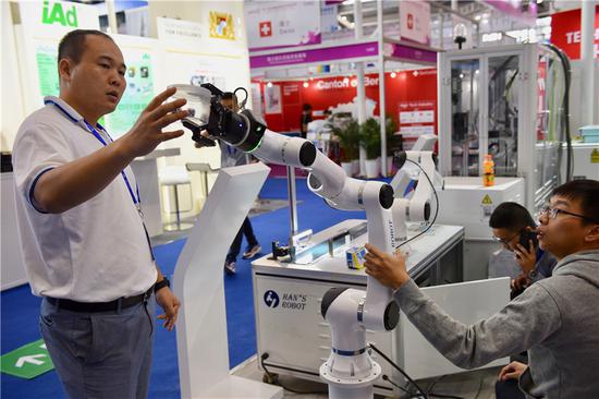 A Han's Laser Tech executive displays a robotic arm at the 20th China High-Tech Fair in Shenzhen, Guangdong province, in November 2018. (Photo provided to China Daily)