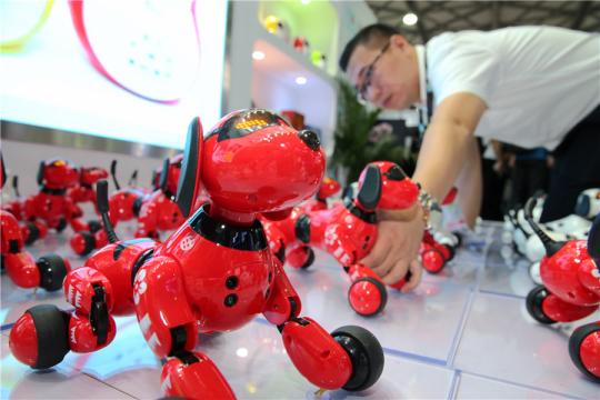 An employee showcases intelligent dogs at the Consumer Electronics Show Asia in Shanghai last year. (Photo by Xu Congjun / For China Daily)