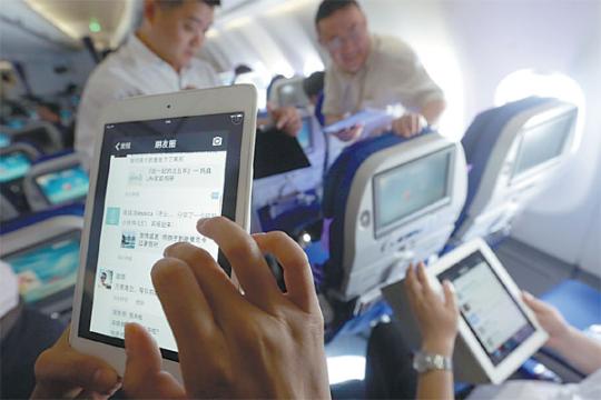 Passengers use WiFi services to surf Internet on mobile gadgets on a flight of China Eastern Airlines. (Photo by Liu Xin/For China Daily)