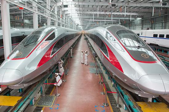 Workers check Fuxing bullet trains in the assembly workshop of CRRC Qingdao Sifang Co in Qingdao, Shandong Province, in June.(Photo by Wu Huapeng/Xinhua)