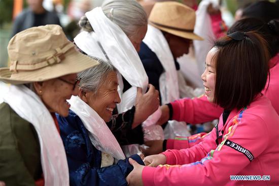 Young people present hada, a white ceremonial silk scarf, to the elderly in an event to celebrate the 60th anniversary of democratic reforms in Tibet, at a community in Lhasa, capital of southwest China's Tibet Autonomous Region, March 23, 2019. (Xinhua/Chogo)