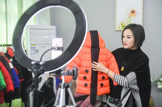 A woman sells clothes through the live webcast platform of Taobao at Zhili Town of Huzhou, east China's Zhejiang Province.(Xinhua/Xu Yu)