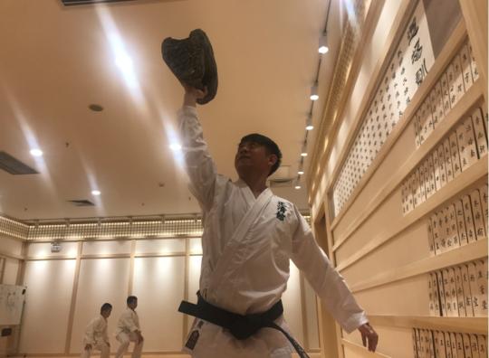 Master Zheng Wenlong in his new studio with one of the Ming Dynasty bricks which was used by his ancestors in training of martial arts. (Photo provided to chinadaily.com.cn)