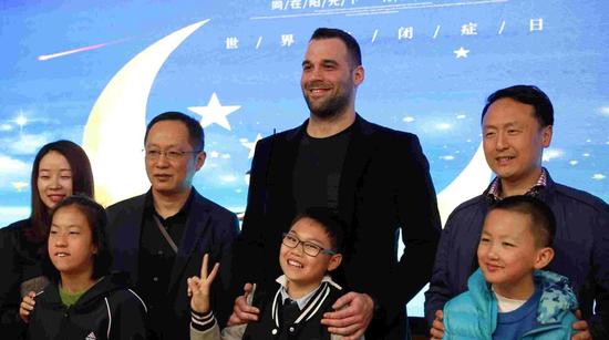 Goran Marinovic (C) poses with children and school staff at a ceremony during which he donates 100,000 yuan to Suzhou Ren'ai School to help its autistic children. /CGTN