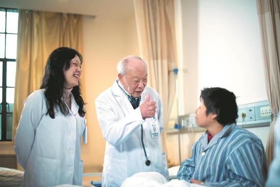 Professor Wang Zhenyi visits a patient with a colleague at Ruijin Hospital in Shanghai. (Provided to China Daily)