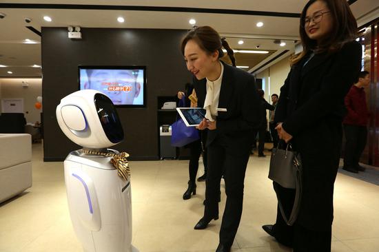 An artificial intelligence-powered robot welcomes a customer in the Xiangyang branch of Ping An Bank in Xiangyang, Hubei Province. (Photo by Yang Dong/For China Daily)