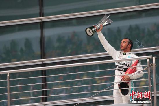 Mercedes driver Lewis Hamilton of Britain celebrates on the podium after winning the Chinese Formula One Grand Prix at the Shanghai International Circuit in Shanghai, China, April 14, 2019. (Photo: China News Service/Yin Liqun)