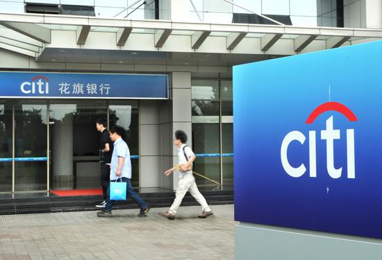 Pedestrians walk past a Citi outlet in Shanghai. (Photo by Jin Rong/For China Daily)
