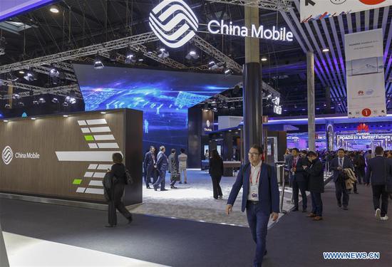 People walk past China Mobile's booth during the first day of the 2018 Mobile World Congress (MWC) in Barcelona, Spain, on Feb. 26, 2018. [Photo/Xinhua]