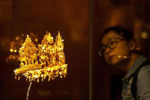 A visitor takes a closer look at a gold crown on display in the Utensils and Ornaments Endlessly Fine exhibition held at Tsinghua University Art Museum. (Photo by Hou Yu/China News Service)