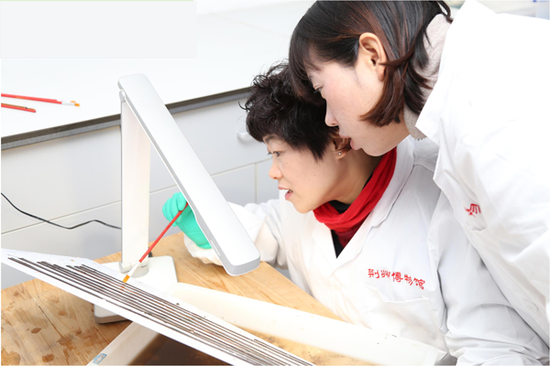 Researchers from Jingzhou Museum clean bamboo and wooden slips in a lab. (Photo provided to China Daily)