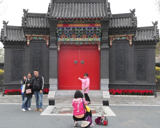 Tourists take pictures in front of the Shanxi garden at the International Horticultural Exhibition in Beijing on Sunday. The facade is represented by the gate of a typical Shanxi compound courtyard. (Photo by WANG JING/CHINA DAILY)