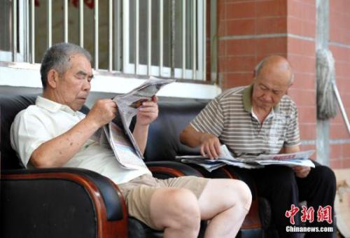 Senior people kill time by reading newspaper. (File photo/China News Service) 