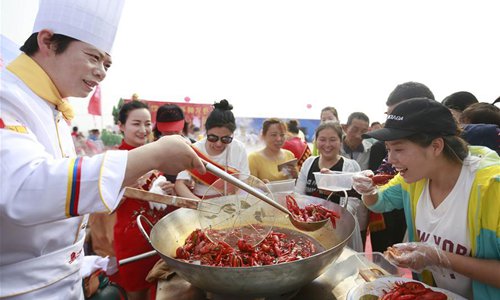Tourists taste the crawfish in Mingzuling town of Xuyi county, East China's Jiangsu Province. (Photo/Xinhua)