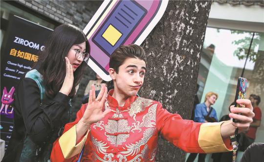 A foreigner in traditional Chinese menswear called Tangzhuang or Tang suit, takes a selfie with a visitor at the Bazinga Hutong Festival, a community event organized by Ziroom to help more foreigners better understand, and adapt to living in, China. (Photo provided to China Daily)
