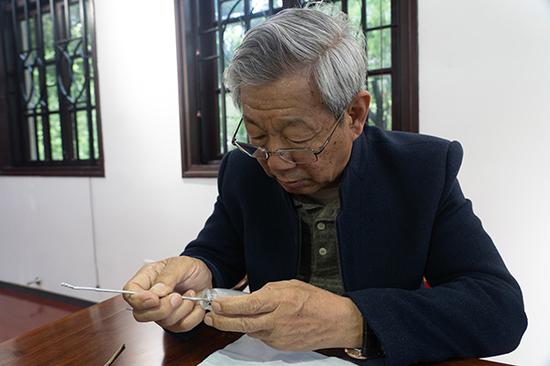 Artist Wang Xiaocheng uses a redesigned Chinese brush to paint inside a snuff bottle.(Photo by Gao Erqiang/China Daily)